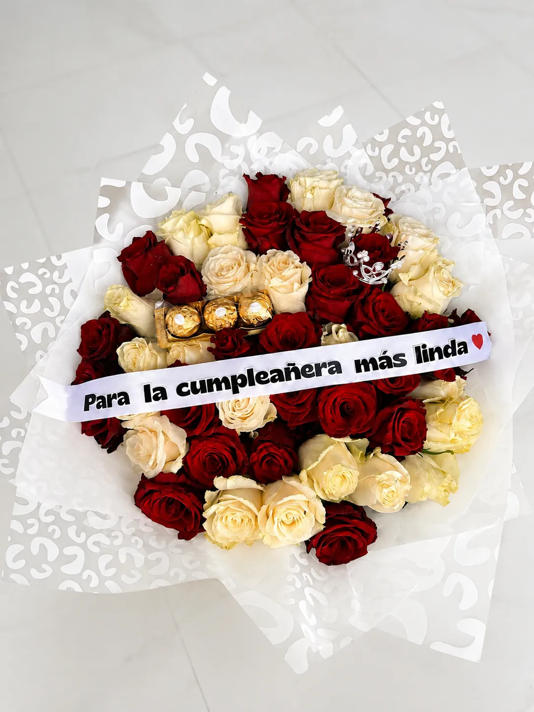 Ramo de rosas rojas y crema con bombones y una cinta de felicitación de cumpleaños.